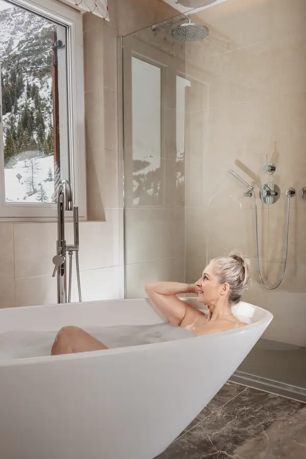 Badezimmer mit freistehender Wanne und Fenster zum verschneiten Wald, Hochformat