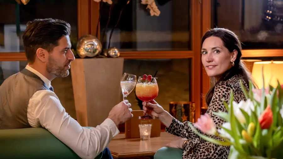 Paar stößt mit farbigen Cocktails an der Hotelbar an