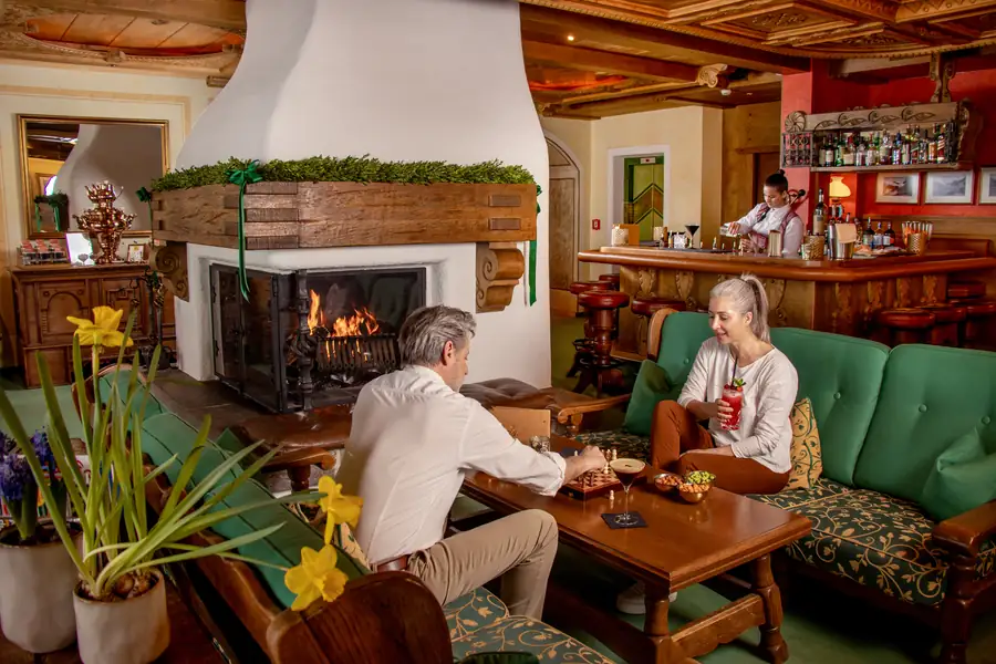 Kaminlounge mit weißem Kachelofen und Bar im Hintergrund