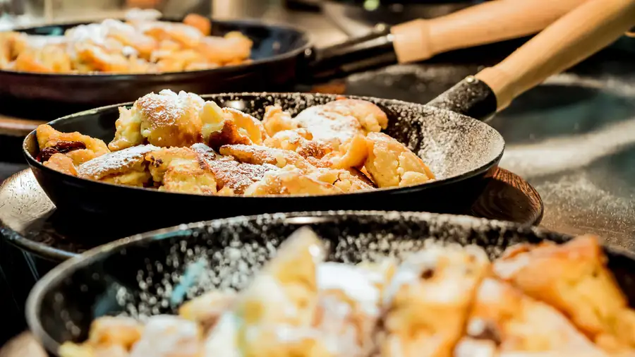 Kaiserschmarrn mit Staubzucker in zwei Pfannen