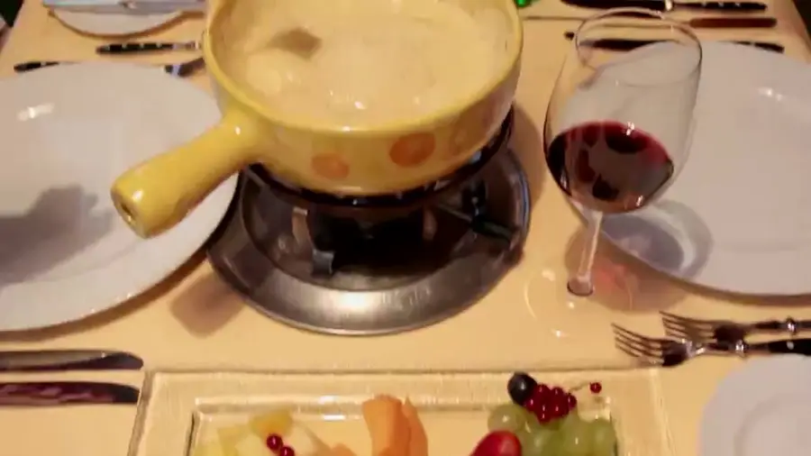 Käsefondue am gedeckten Tisch mit Rotwein