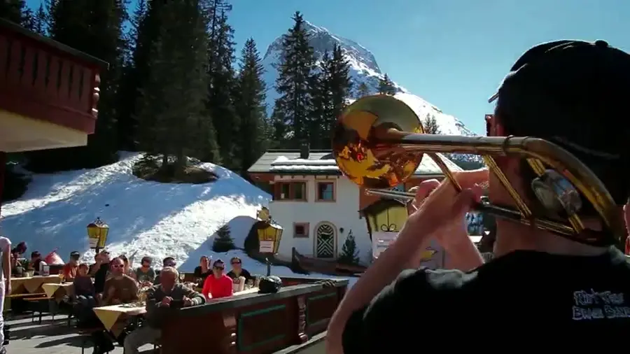 Blaskapelle auf der Sonnenterrasse vor verschneiten Bergen