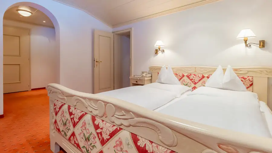 Hotelzimmer mit geschnitztem Holzbett und Blumenwäsche
